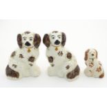 A pair of Staffordshire pottery seated spaniels, together with another smaller example. Largest