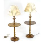 A pair of 20thC lamp tables with turned stems and circular dished shelves above moulded bases and