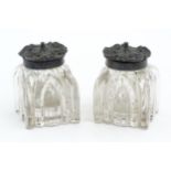 A pair glass inkwells with cast scrolled lids. Approx. 2 1/2" high (2) Please Note - we do not