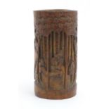 An Oriental bamboo vase / brush pot with carved decoration depicting sage figures in a woodland