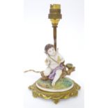 A Continental gilt metal table lamp with ceramic figure depicting a cherub holding a bird. Bears old