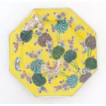 A Chinese octagonal plate with a yellow ground decorated with butterflies, flowers and foliage.