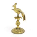 A Victorian gilt metal pedestal stand surmounted by a model of a peacock, possibly a pocket watch