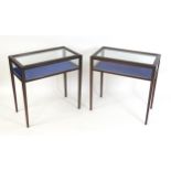 A pair of mid 20thC vitrines / display cabinets with hinged glass tops and raised on tapering