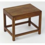 A mid 20thC walnut stool with a rectangular top and a peg jointed base with chamfered legs and