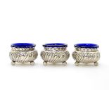 Three silver salts with embossed decoration on three ball feet, hallmarked 1897, maker Thomas Hayes.