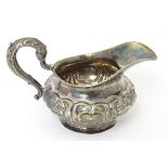 A 19thC Irish silver cream jug with embossed floral and foliate decoration, hallmarked Dublin