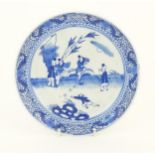 A Chinese blue and white plate decorated with figures in a garden landscape with apples. Approx. 8