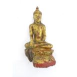 An Asian carved wooden model of a seated Buddha with polychrome decoration, the base with stylised