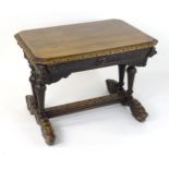 A late 19thC oak writing desk / centre table, having a canted top above a heavily carved frame