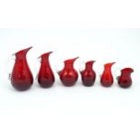Assorted red glass jugs with clear class handles. To include some Whitefriars examples. The