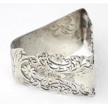 A silver napkin ring of triangular form with floral and foliate decoration and pierced detail,
