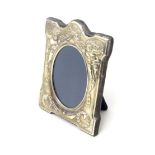 An easel back photograph frame with embossed silver surround depicting cherubs and swags, hallmarked