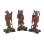 Three Oriental carved wooden figures to include an elder with a staff, etc. Each on a carved