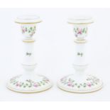 A pair of Royal Worcester candlesticks with banded rose and foliate detail and gilt highlights.