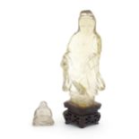 Two Oriental rock crystal style carved items comprising a small seated Buddha, and a deity figure on