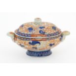 A sauce tureen and cover with twin handles decorated in the Imari palette with scrolling flowers and