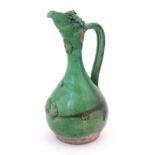 A Turkish Canakkale pottery jug / ewer with a green glaze. Approx. 14" high Please Note - we do