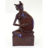 An Indonesian wooden carving modelled as a seated man playing a drum. Signed Bali under. Approx. 12"