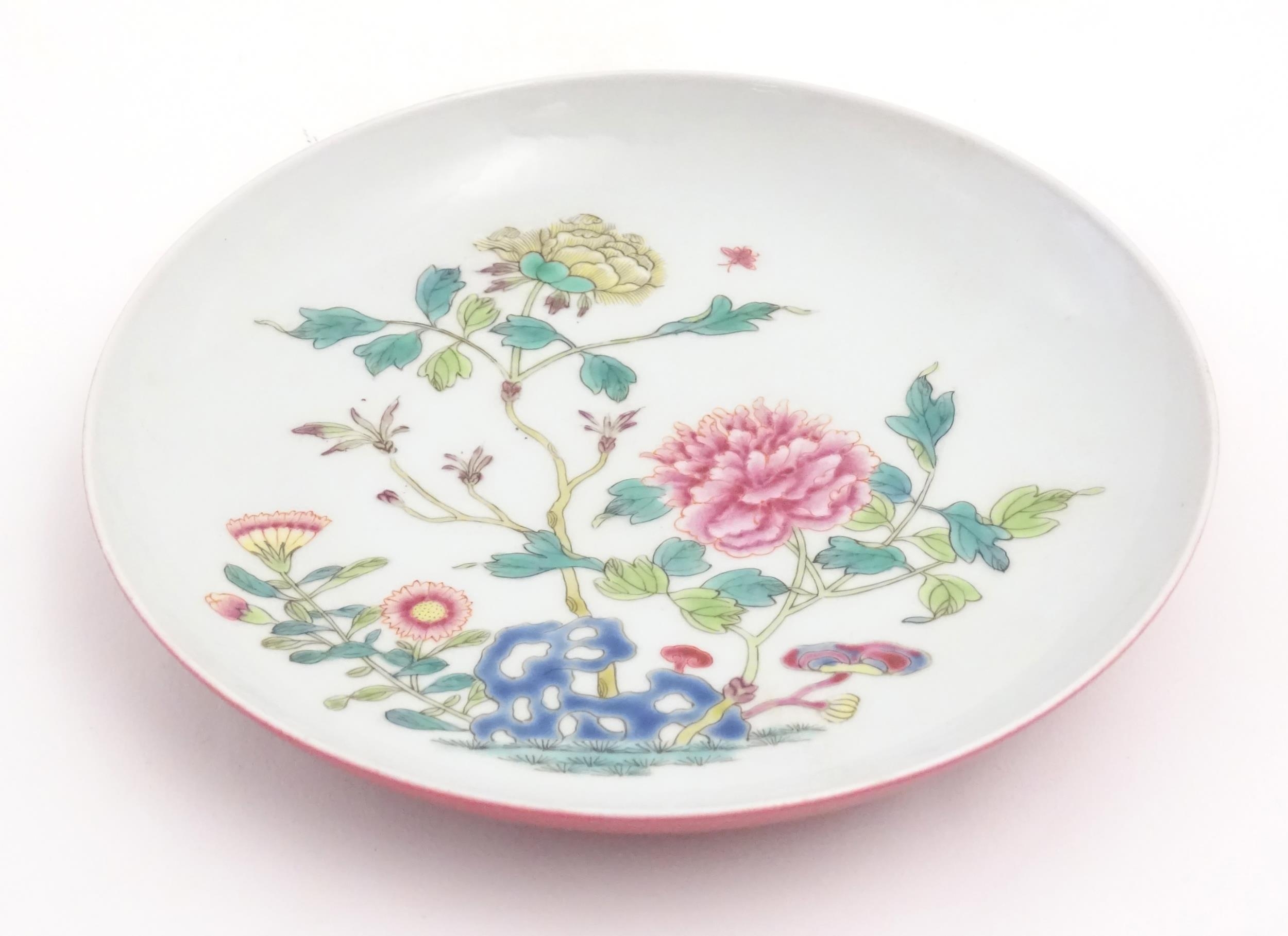 A small Chinese famille rose plate decorated with a stylised rocky outcrop with flowers and foliage. - Image 2 of 5