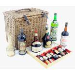 An old wicker hamper containing assorted fortified wines / spirits / liqueurs, etc. to include
