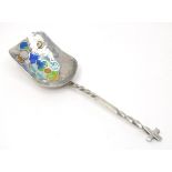 A silver sugar shovel, the hammered bowl with enamel decoration, the twist handle surmounted by a