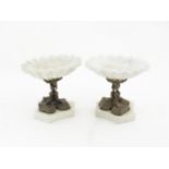 A pair of early 20thC tazzas with white marble shell formed bowls and triform bases, the cast