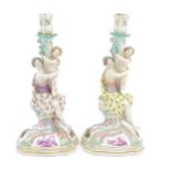 A pair of Continental porcelain figural candlesticks on shaped bases with scrolling floral and