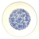 A Chinese blue and white plate decorated with scrolling floral and foliate detail. Character marks