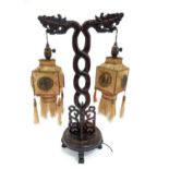 An Oriental carved table lamp of twin branch form with dragon detail and twin silk shades. Approx.