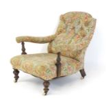An early 20thC Howard style armchair with a button back and deep seat, the arms raised by turned