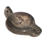 Roman. A Roman terracotta oil lamp decorated with a naked female washing