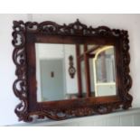A 1920s CAROLEAN STYLE CARVED OAK AND LEATHER FRAMED WALL MIRROR