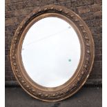 A 19TH CENTURY HEAVILY MOULDED GILT OVAL FRAMED MIRROR