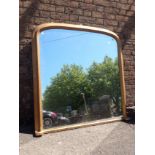 A GILT FRAMED ARCHED TOP OVERMANTEL MIRROR