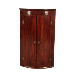 A GEORGE III MAHOGANY BOW-FRONT HANGING CORNER CUPBOARD