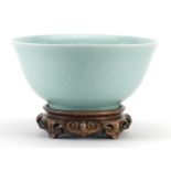 Chinese porcelain bowl on carved hardwood stand having a celadon glaze decorated under glaze with