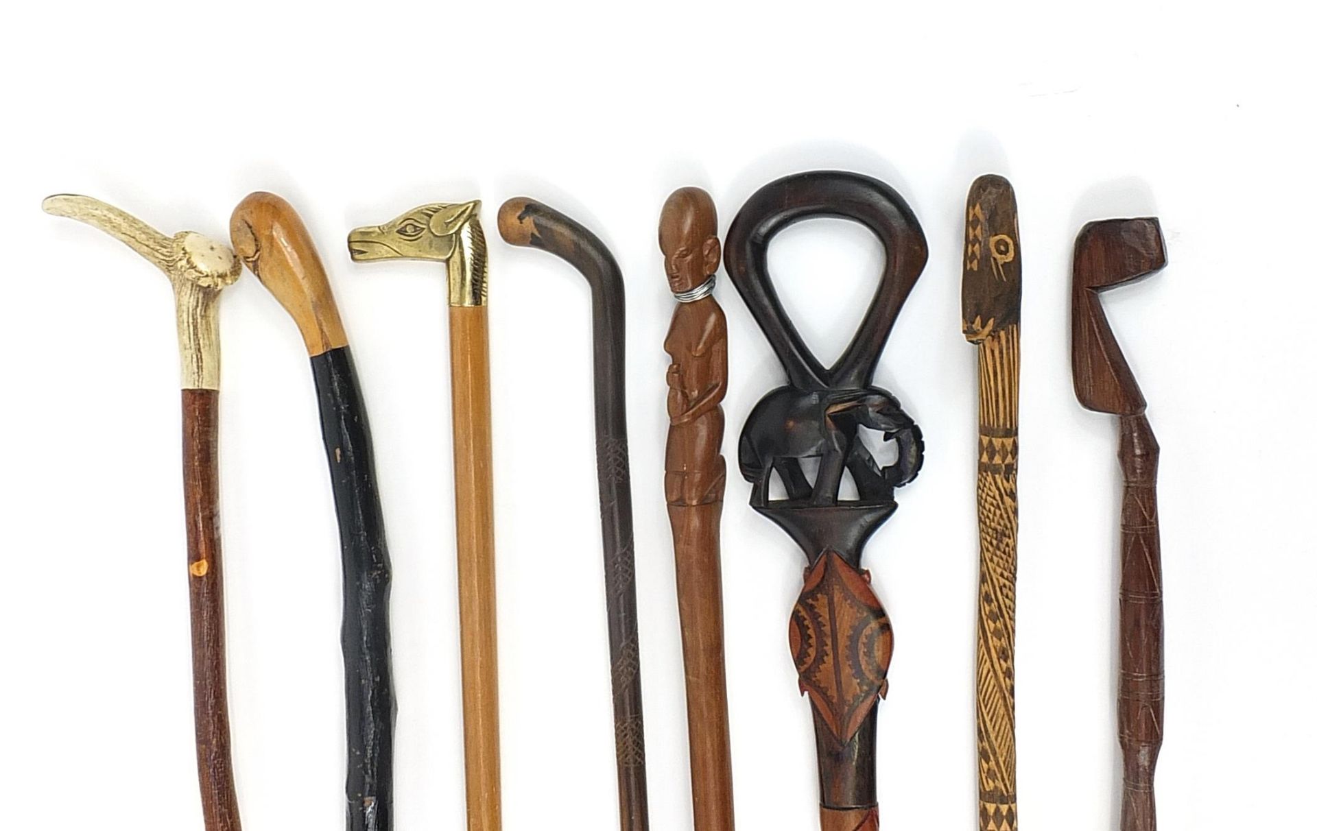 Eight tribal interest wooden walking sticks including one with antler horn handle, each