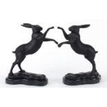 Pair of patinated bronze boxing hares raised on shaped marble bases, 29cm high Overall in