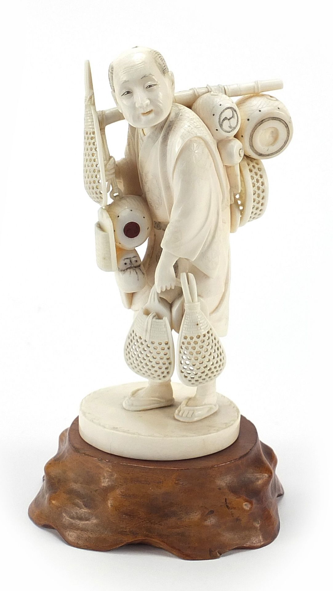 Good Japanese carved ivory okimono of a fisherman raised on a hardwood stand, inset red plaque