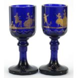 Pair of 19th century cobalt blue glass goblets gilded with children playing and lovers, each 20.