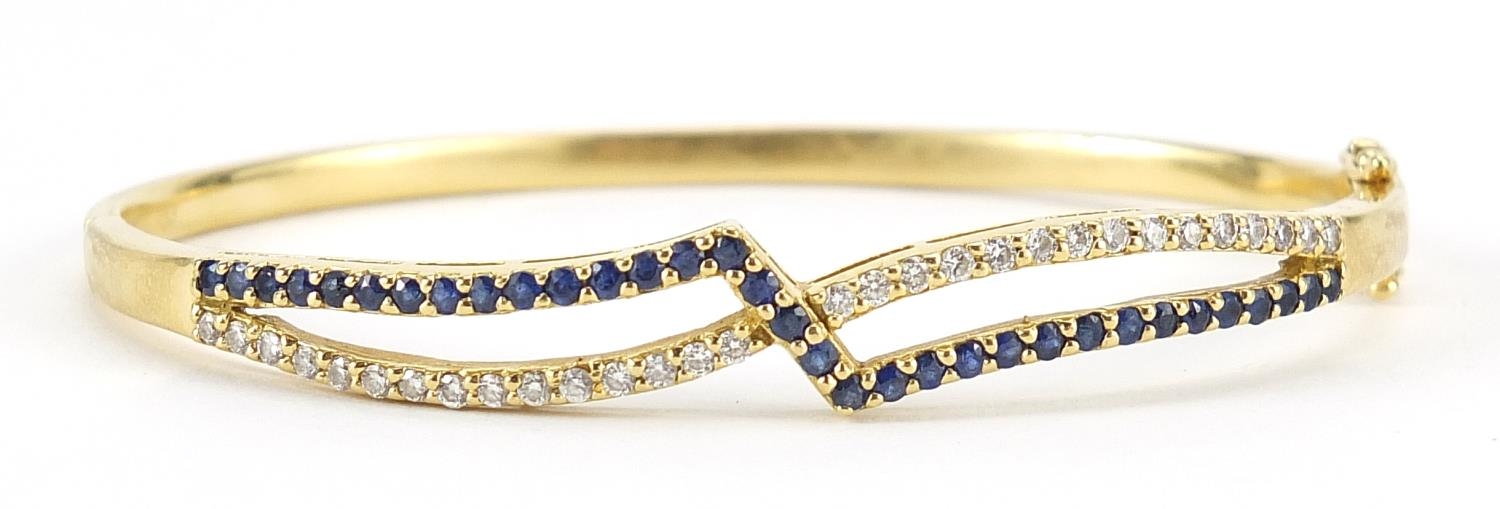 18ct gold diamond and sapphire crossover hinged bangle, 6.5cm wide, 17.5g