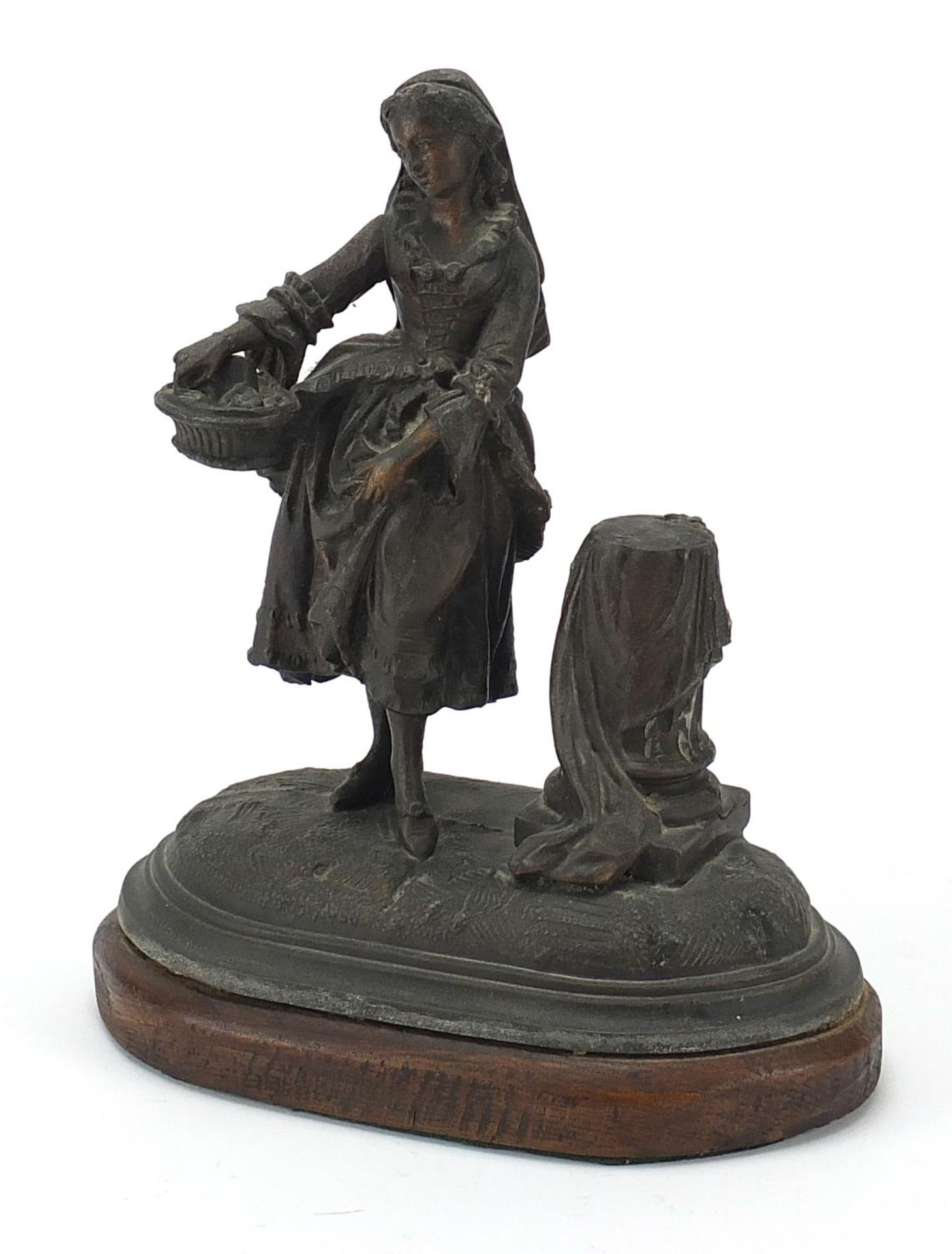 19th century patinated spelter study of a female holding a basket raised on an oval oak base, 19.5cm
