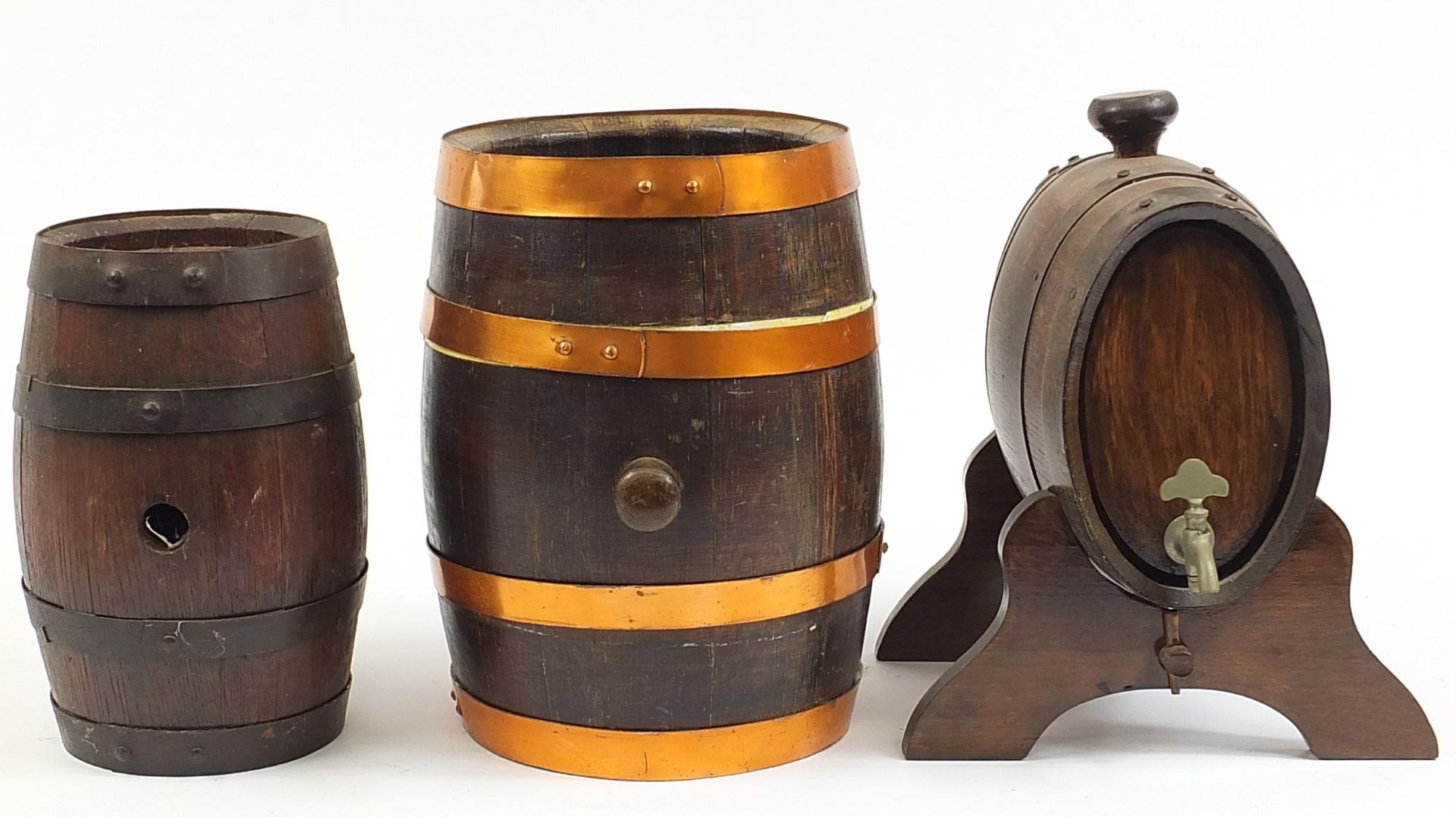 Three oak barrels with metal mounts including one on stand, the largest 35cm in length