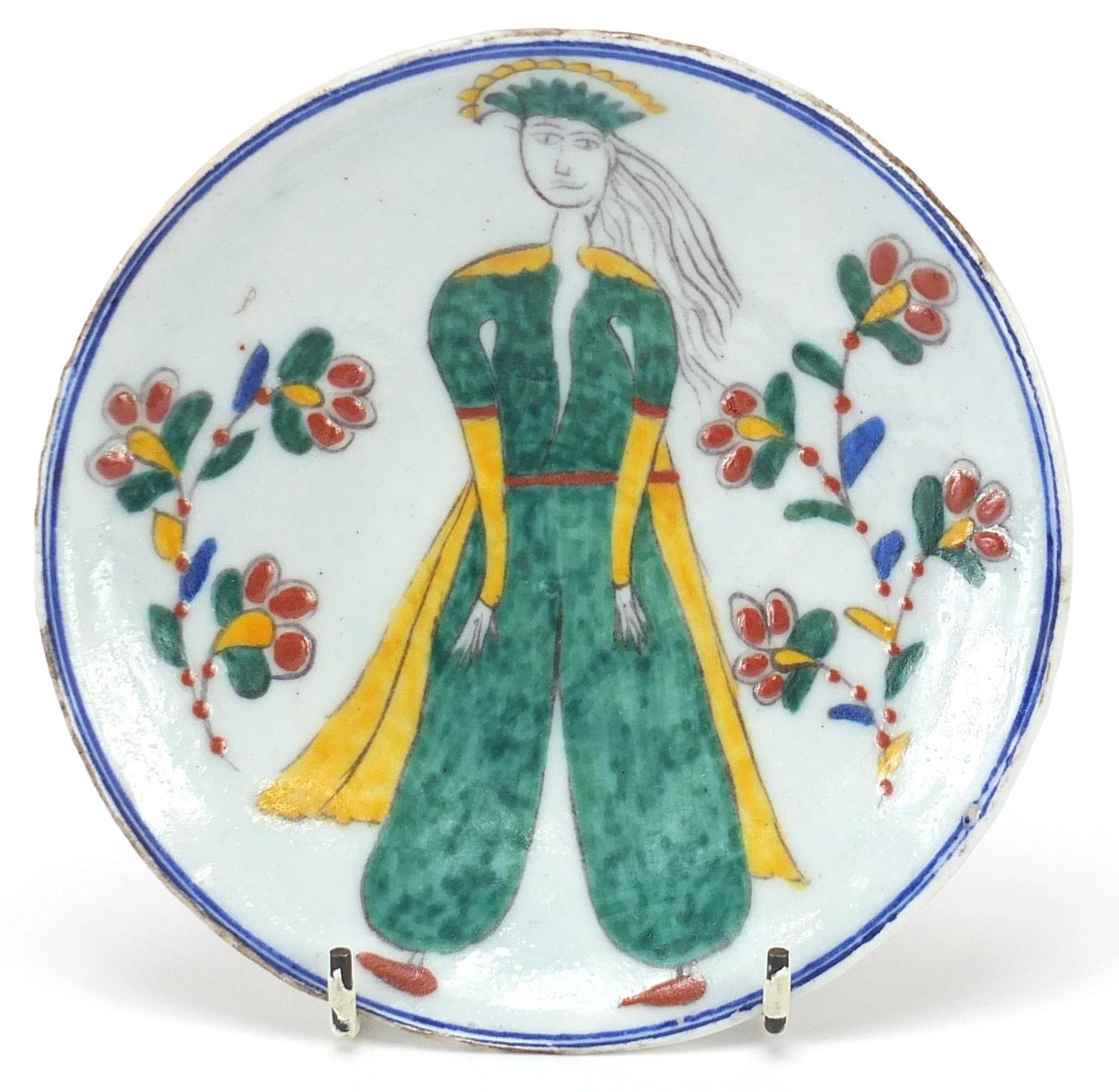 Turkish pottery shallow dish hand painted with a figure and flowers, 14.5cm in diameter