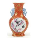 Chinese iron red ground porcelain vase with twin handles hand painted in the famille rose palette