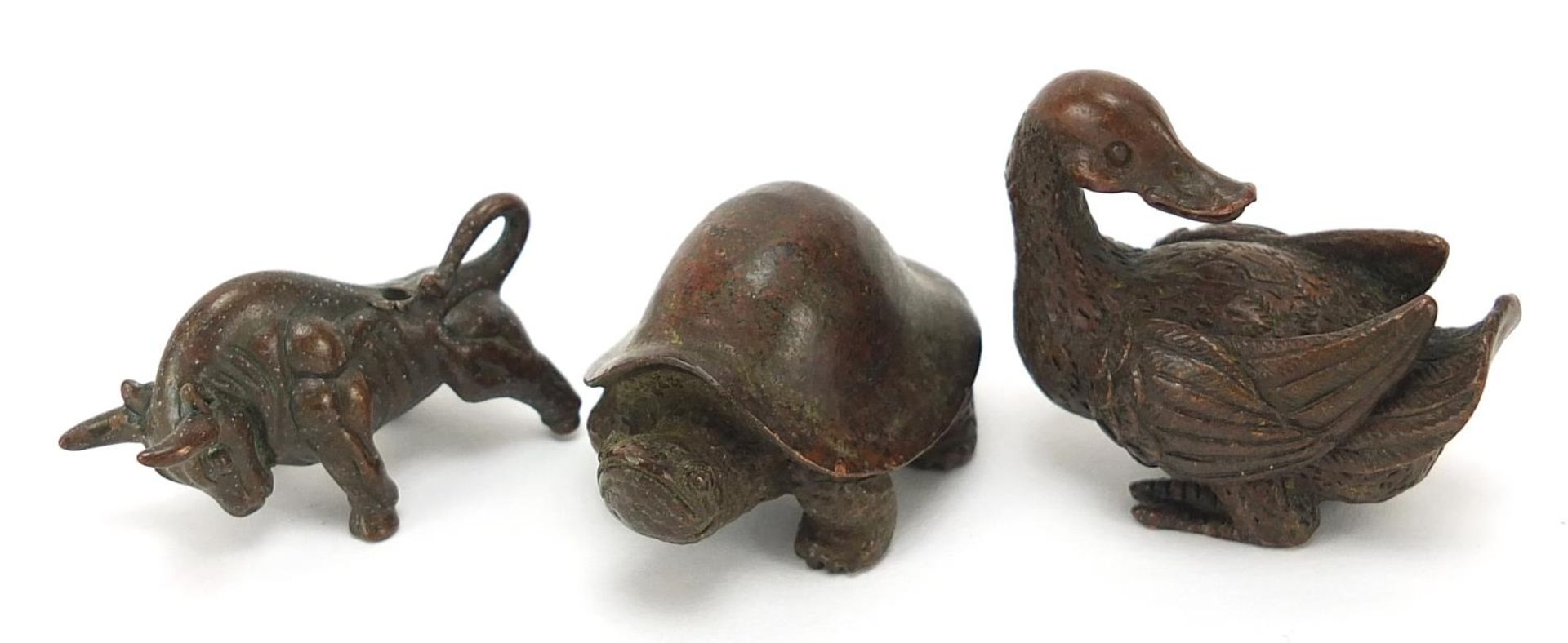 Three Japanese patinated bronze animals comprising duck, tortoise and bull, each with impressed