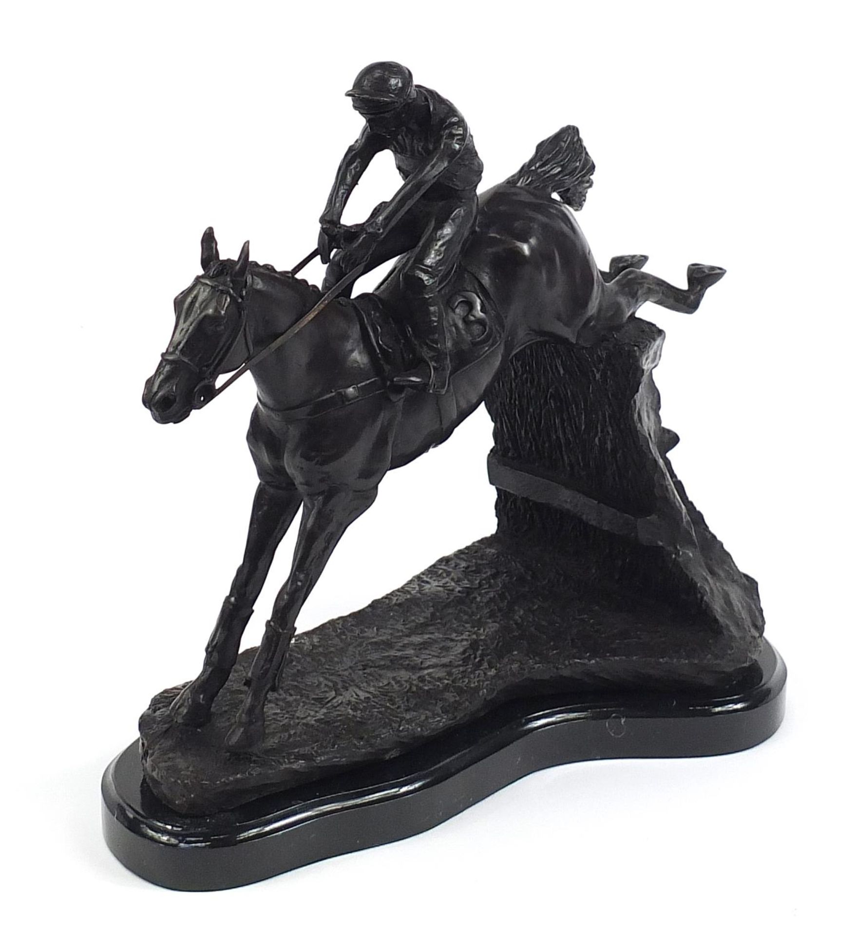 Large patinated bronze study of a jockey on horseback jumping a hurdle, 34cm in length