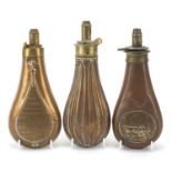 Three 19th century copper and brass powder flasks including one embossed with two hounds,