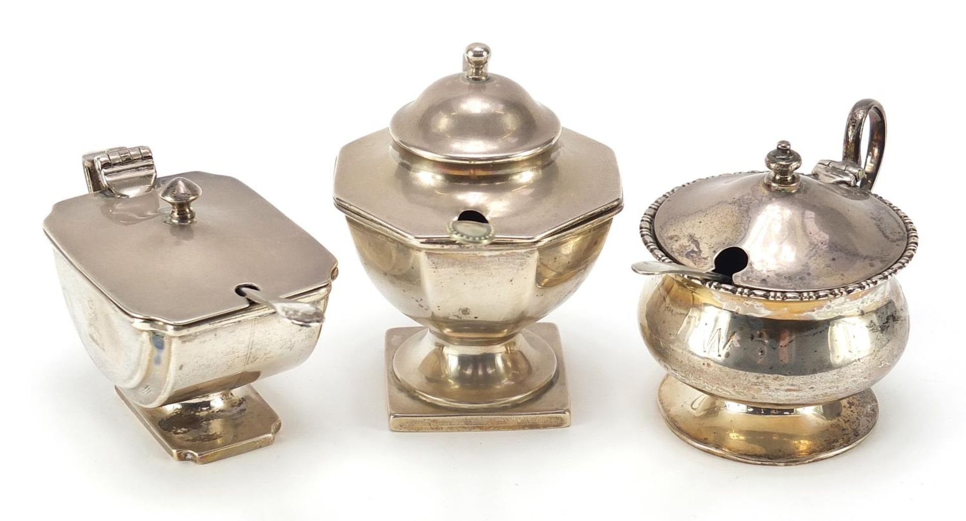 Three Edwardian and later silver mustards with blue glass liners, two with silver spoons and one